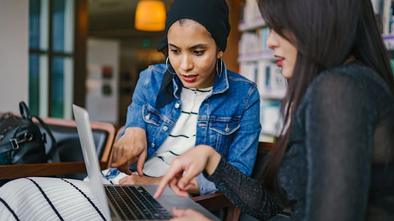 Business Women collaborate on same laptop